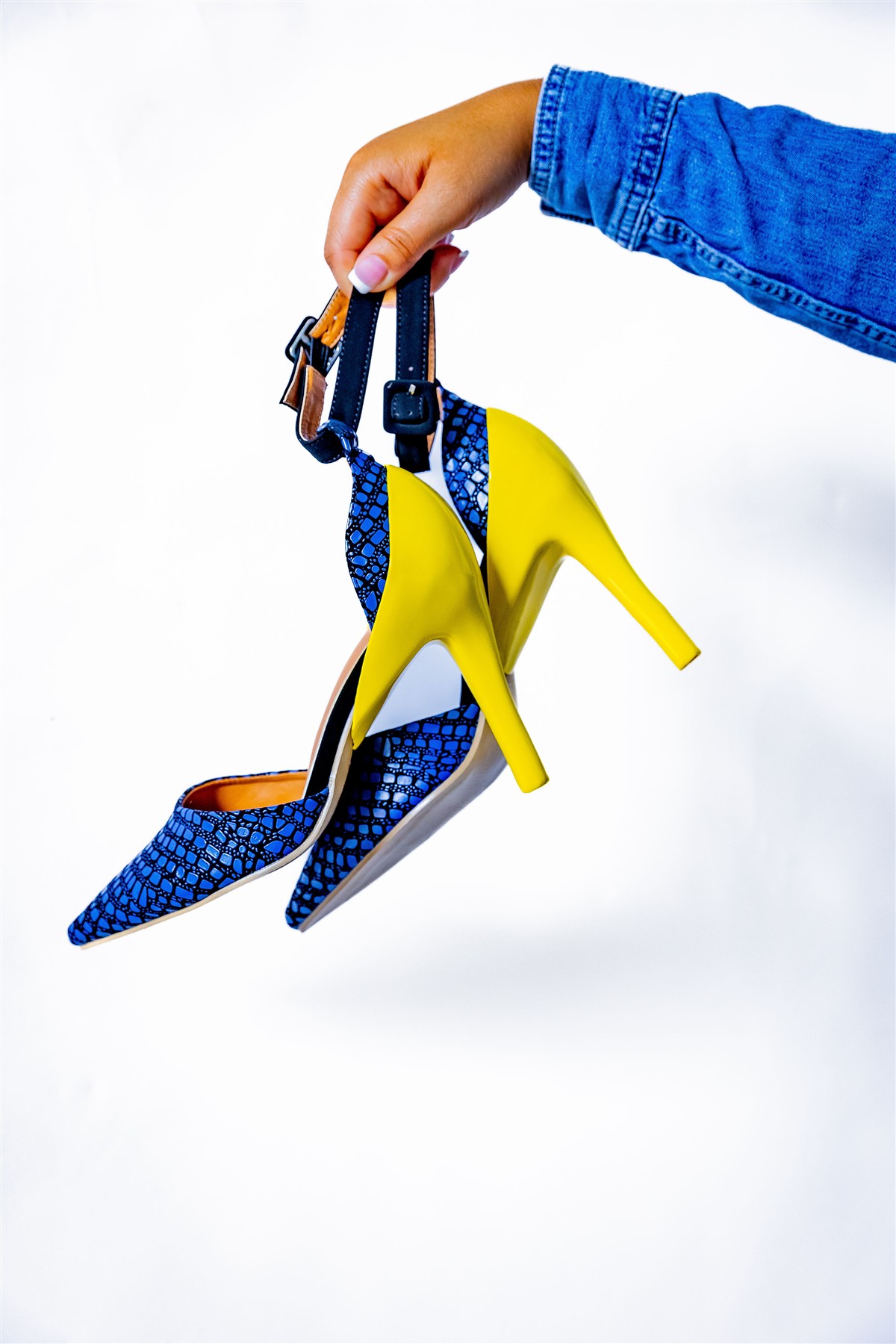 Blue slim high heels with bright yellow heel covers held against a white backdrop